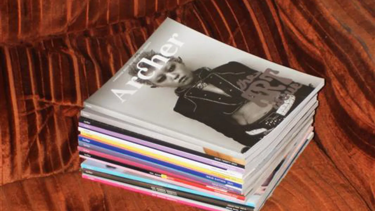 A stack of Archer's print magazines on a velvet couch.