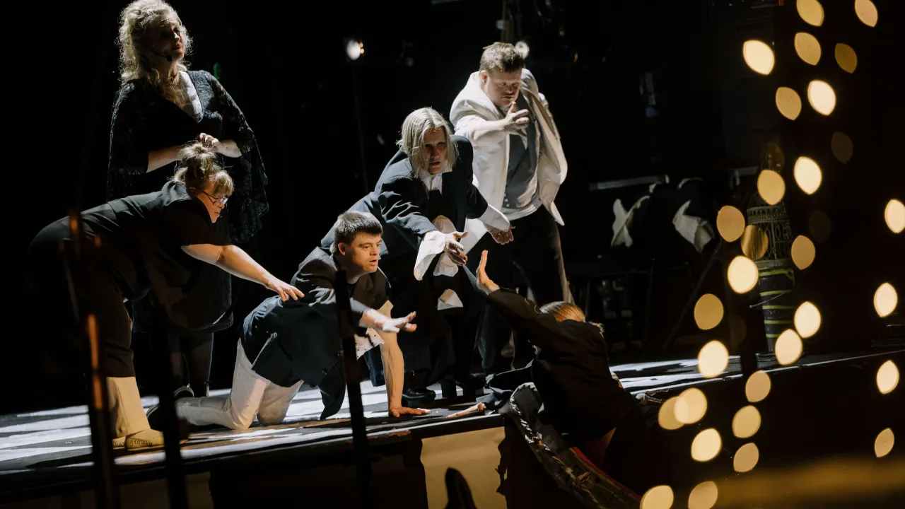 A dramatic scene from 'Relâche: The Last Dance on Earth' shows SEE artists with and without disability leaning, stretching and reaching out, embodying the power of connection through performance.