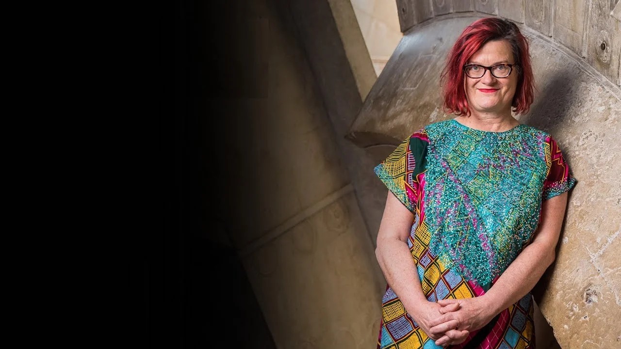 A photo of Fiona Winning, a woman with red hair and glasses, smiling