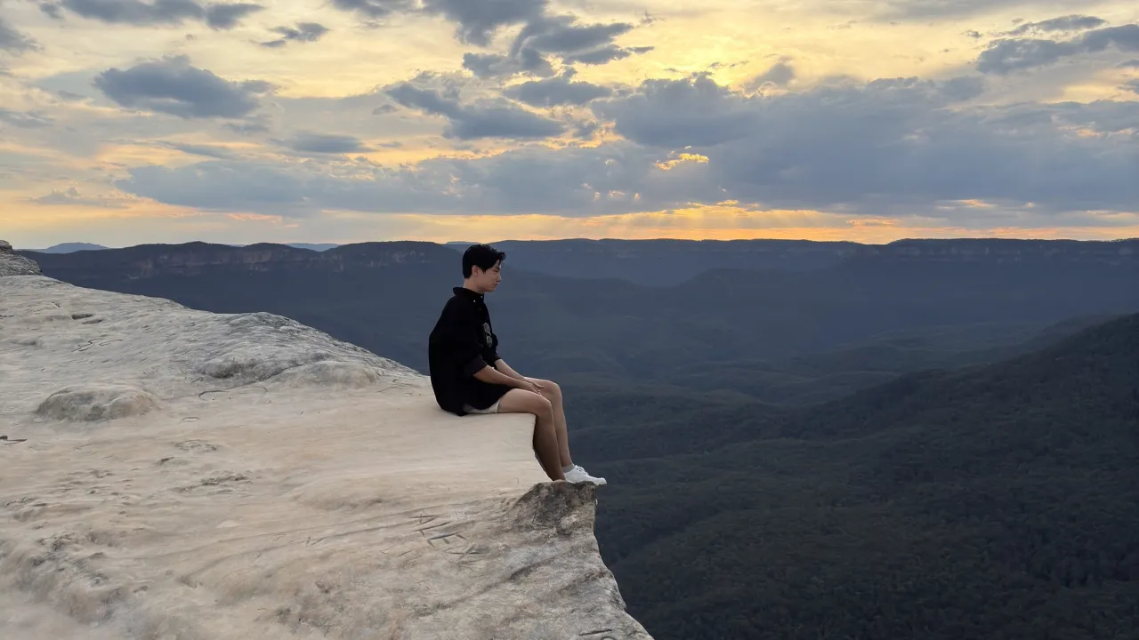 Naraphat Sakarthornsap sits on the edge of a cliff at dusk