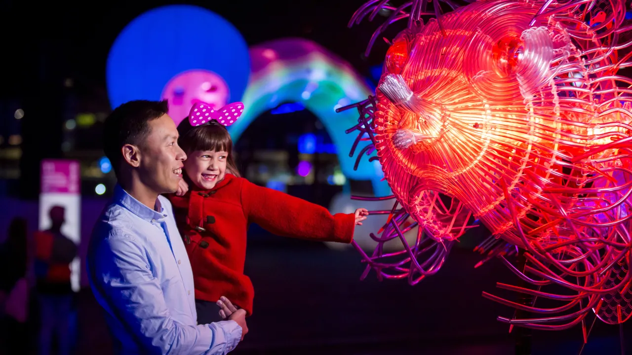 Family enjoying a close-up view of the Fugu light installation at First Fleet Park, The Rocks during Vivid Sydney 2018