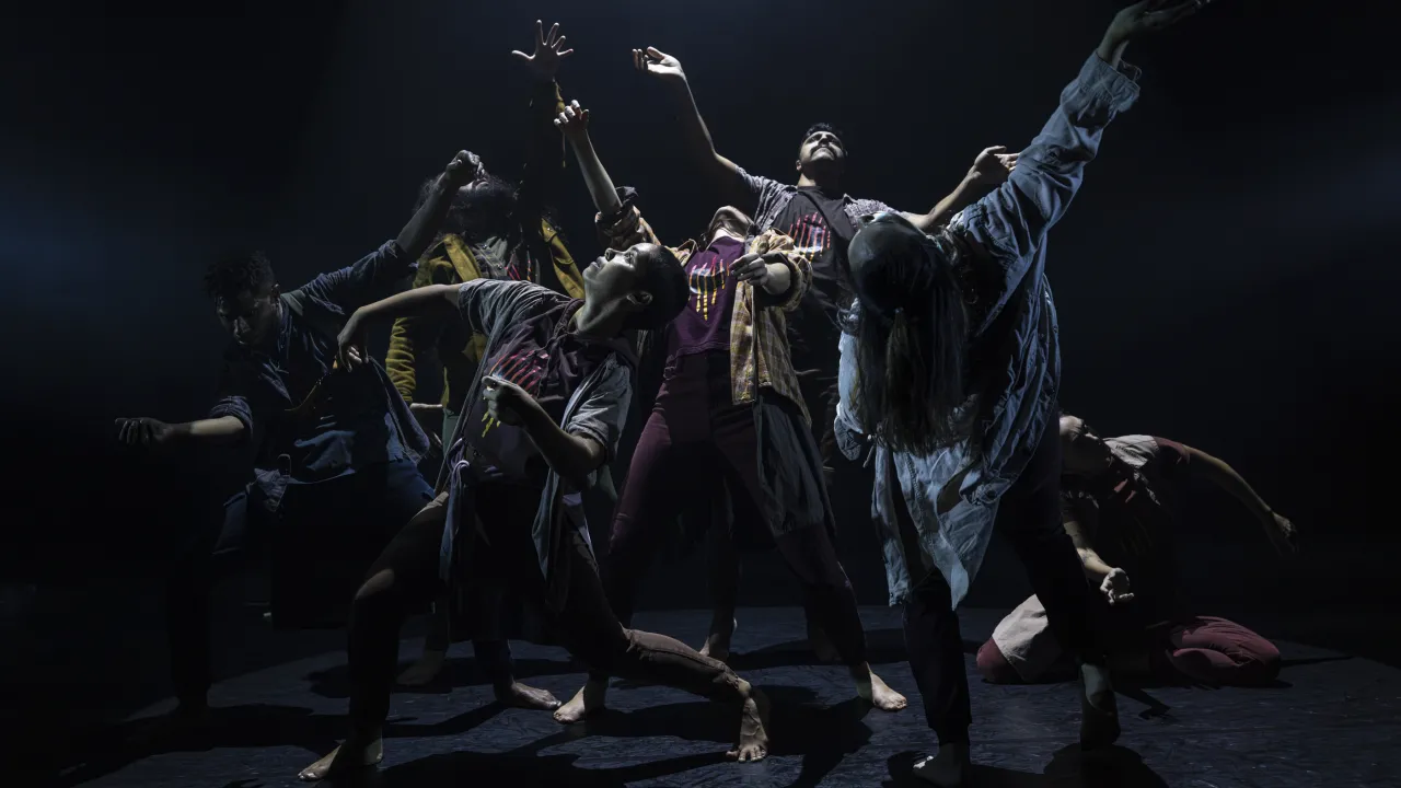 Image of a First Nations dance ensemble on stage. The performers are crouched in a group with arms reaching in different directions. The image is from SILENCE by Karul Projects performed at Sydney Opera House 2024.