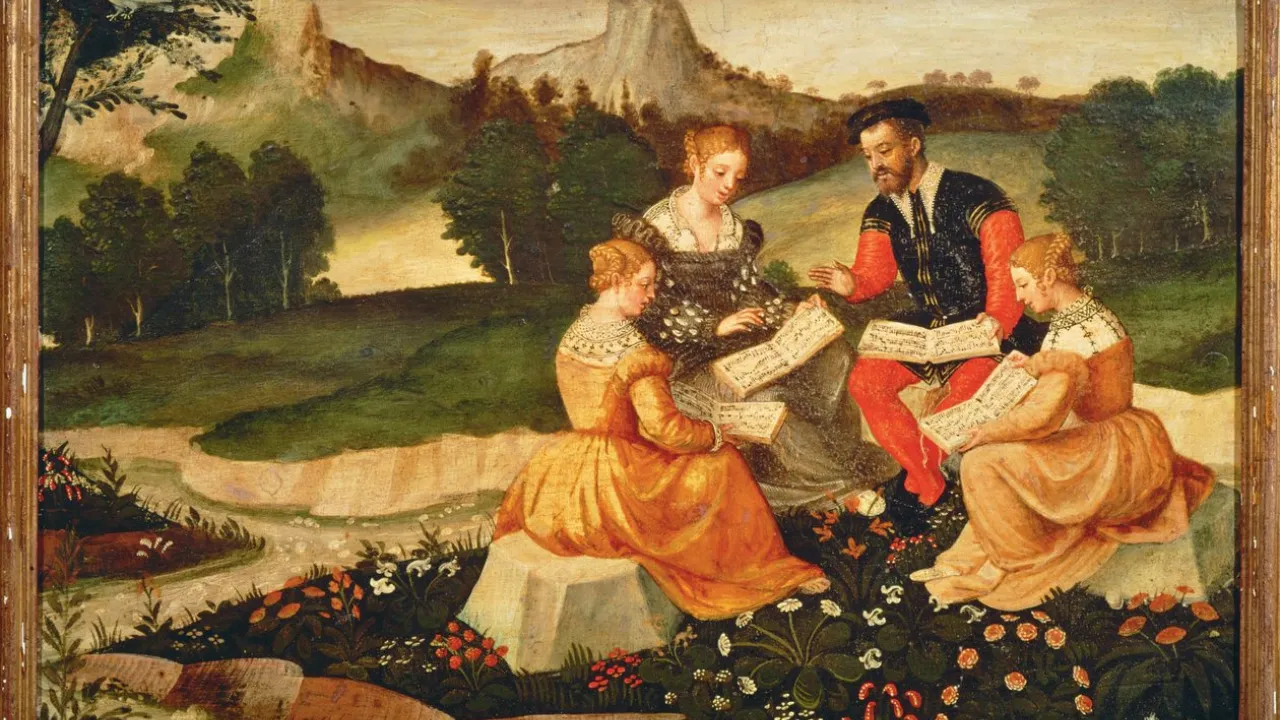 The image depicts a Renaissance style painting of four figures, three women and one man, sitting outdoors on rocks and grass near a gentle stream. They appear to be studying or singing from open sheet music. The women wear long elegant dresses, while the man wears a doublet and hat. The background shows trees, mountains, and a partly cloudy sky. Flowers grow in the foreground, and a white bird perches in a tree on the left. The scene conveys a serene pastoral setting with a focus on music and learning.
