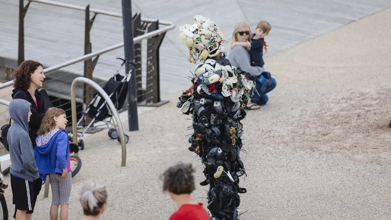 People standing outside looking at a person in a suit and helmet covered with computer mouse's.