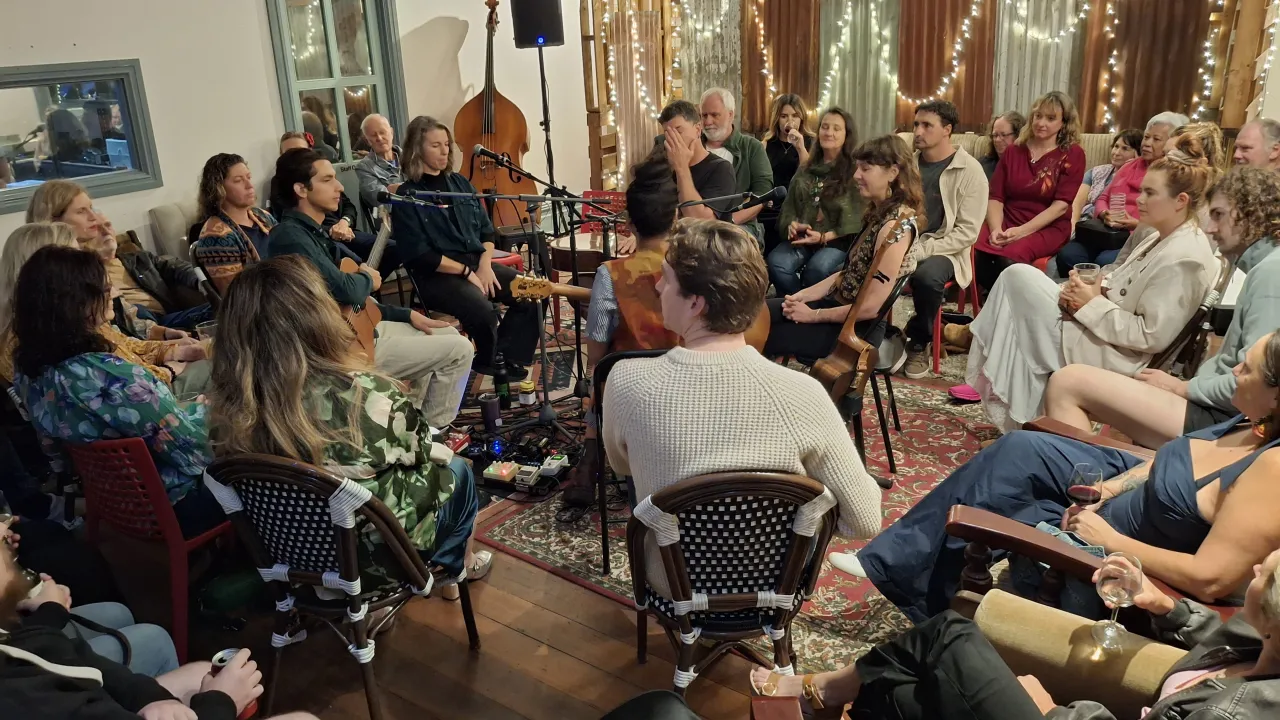 Image shows audience seated in circular style to listen to songwriters and musicians 'in the round' upstairs at Regional Sounds foreshore music hub in Geraldton, July 2025.