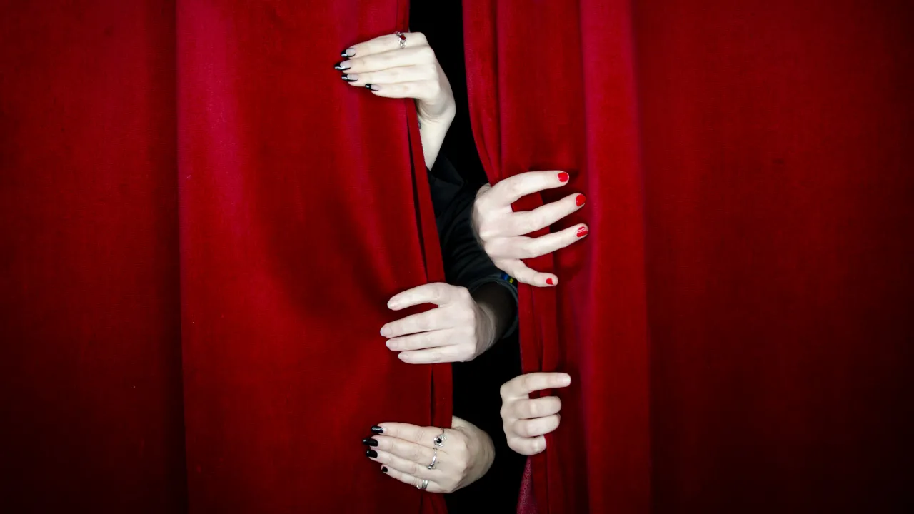 Five hands opening a red curtain