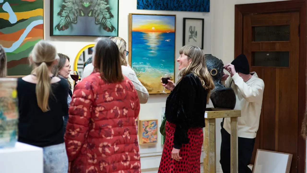 Six people enjoying an exhibition surrounded by various artworks