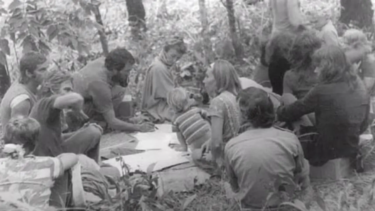 Black-and-white archival photograph of community members gathered in the Kuranda rainforest around plans at the first meeting that led to the creation of the Kuranda Amphitheatre almost 50 years ago.