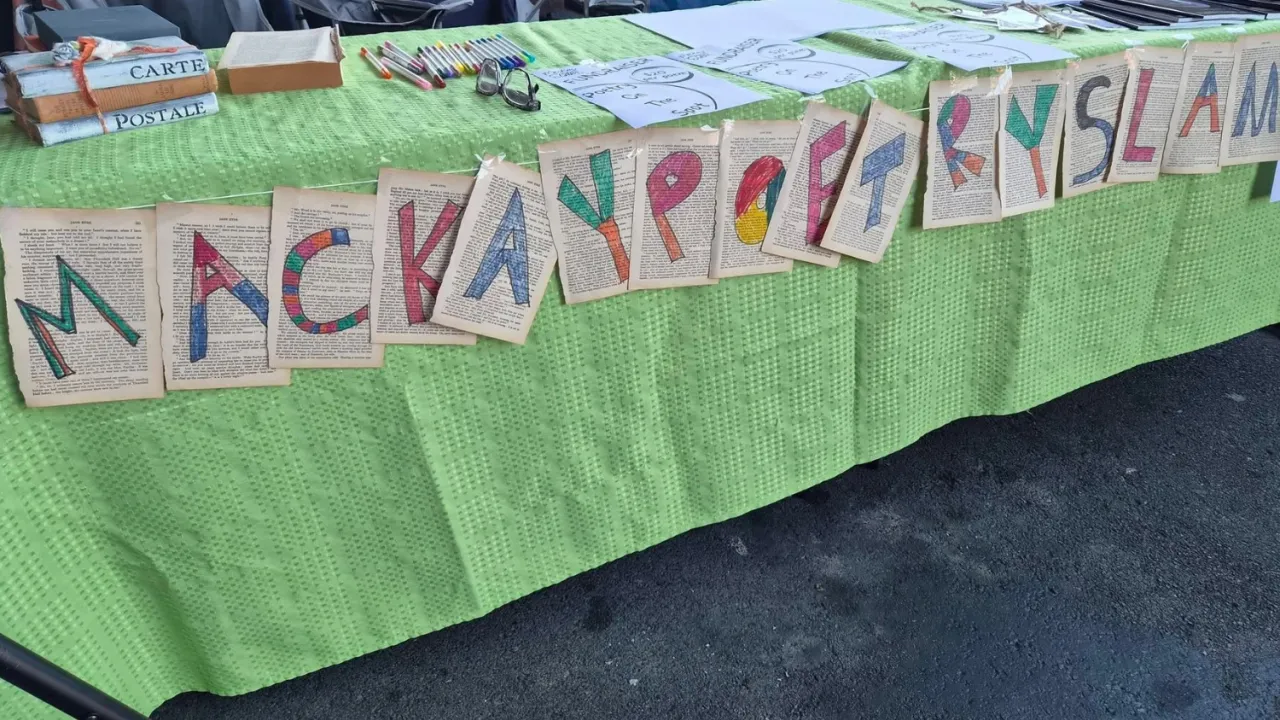 Long outdoor market table with Mackay Poetry Slam banner made from pages of books