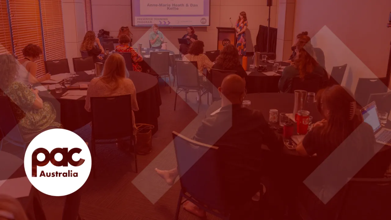A transparent photograph of people seated at tables listening is to people speaking at front of room, overlaid with a red wash and the white PAC Australia logo in the bottom corner