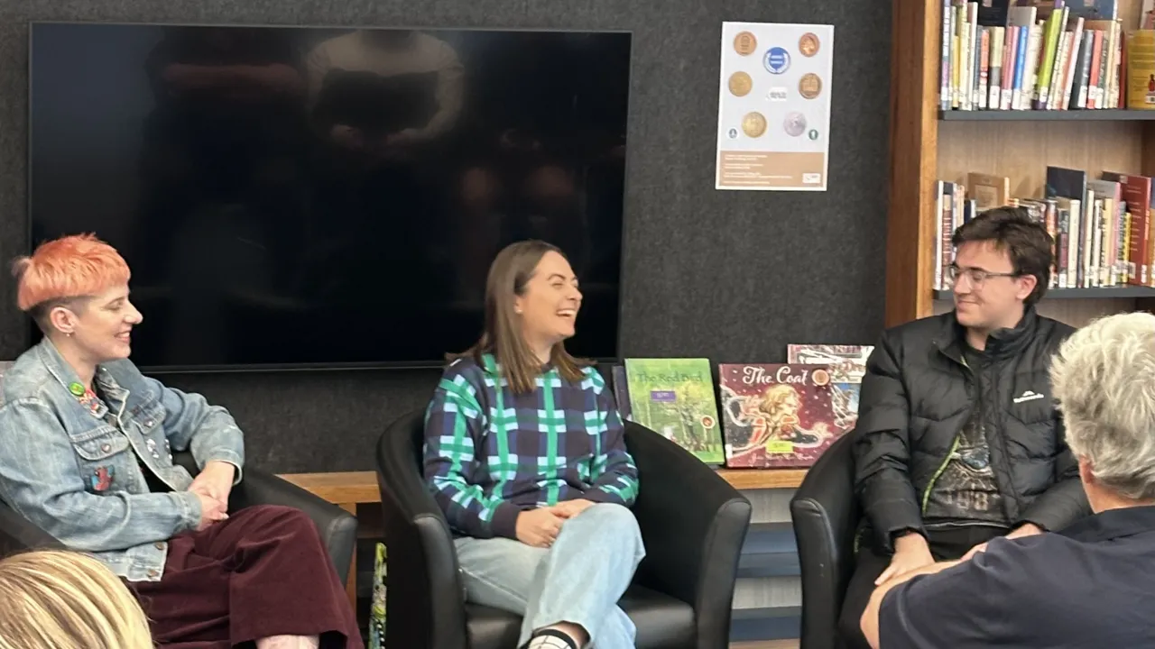 Three people engaged in a conversation. All appear to be smiling.