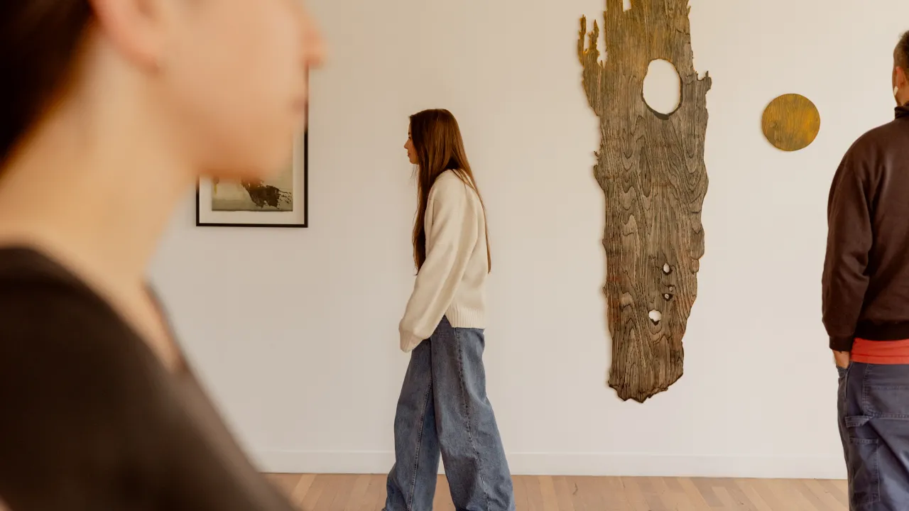 A woman walks past a large timber artwork with two parts, Mother and Child by GW Bot 