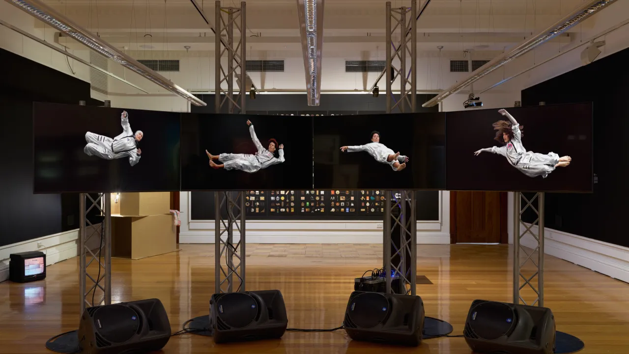A gallery with a multi channel video work showing a person in different poses.