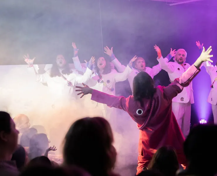 Performers reaching for the sky in a room with haze