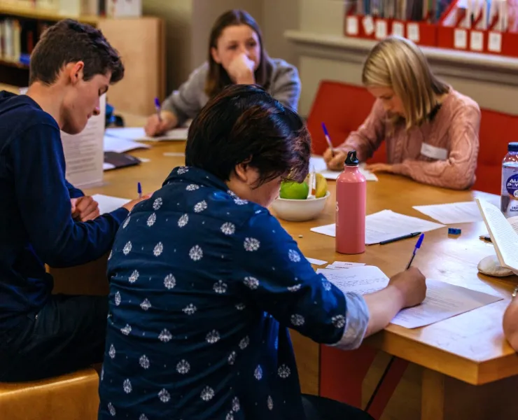 A group of people sitting around a table writing