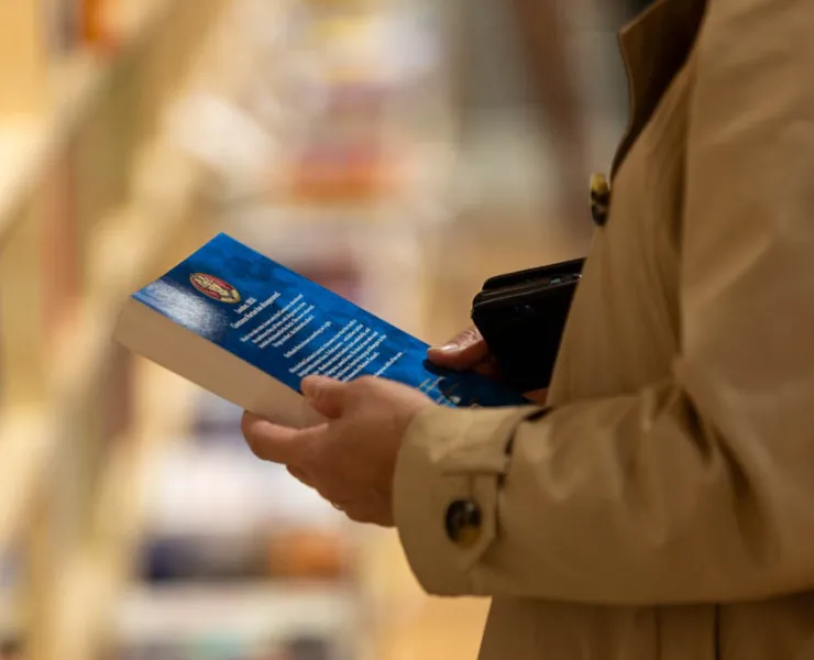 Person holding a book, reading the back cover
