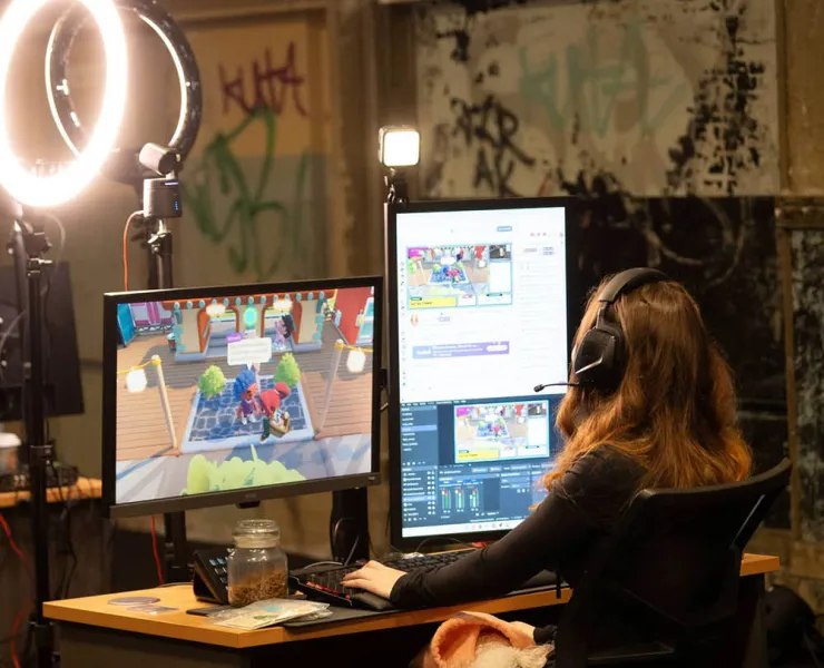 Woman coding a game sitting in front of two monitors