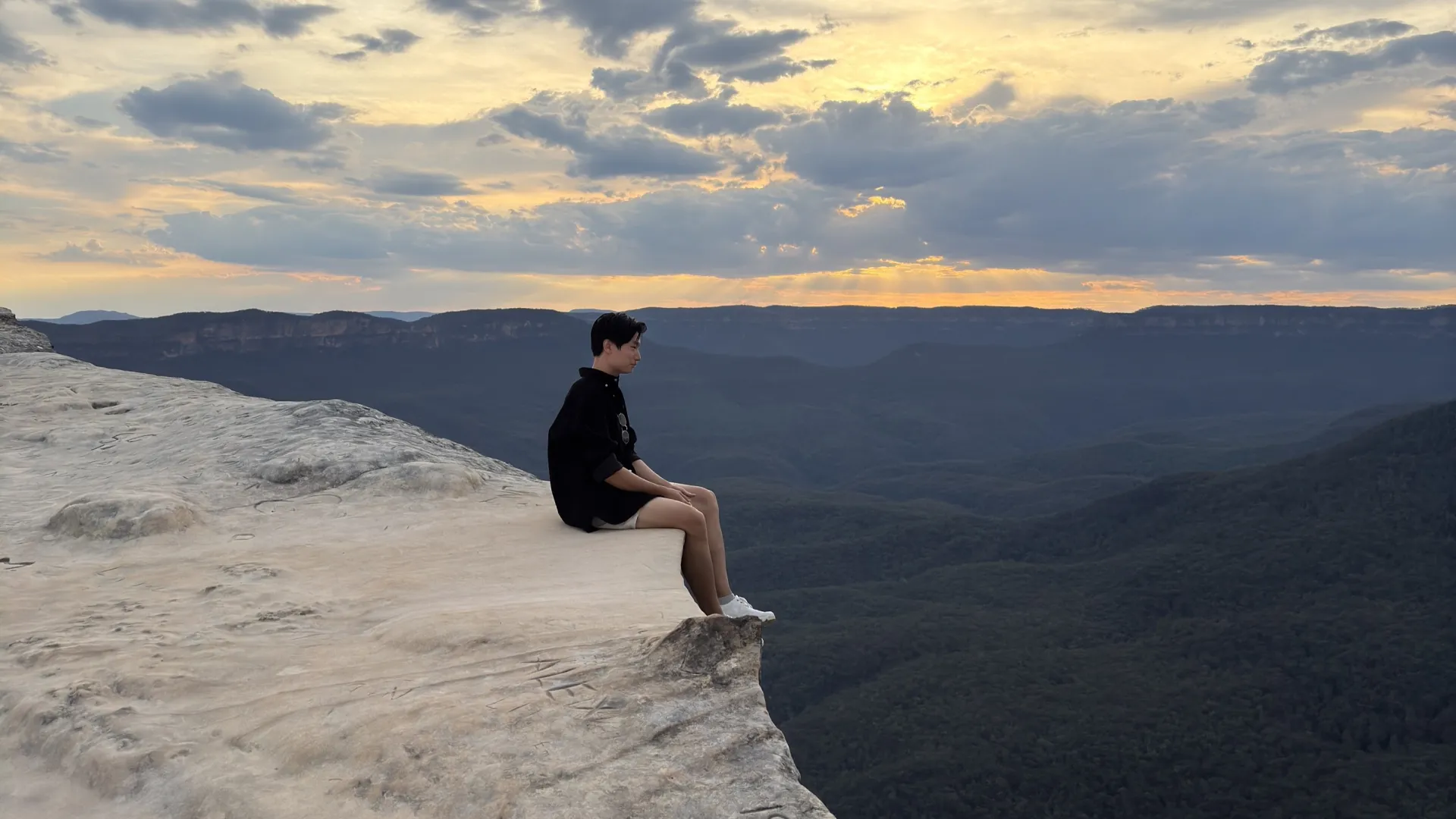 Naraphat Sakarthornsap sits on the edge of a cliff at dusk