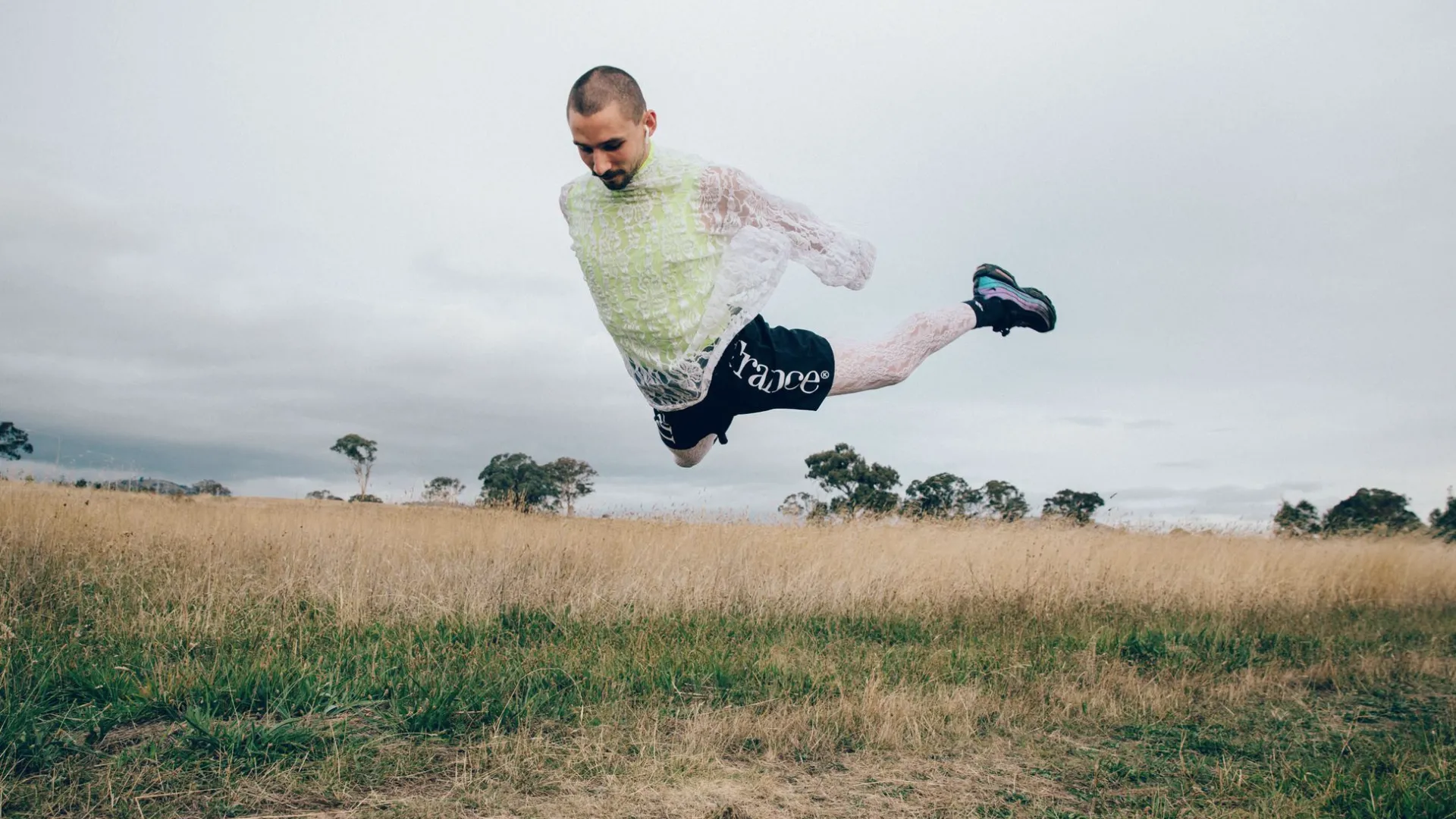 A photo of a dancer jumping mid air in a large field.