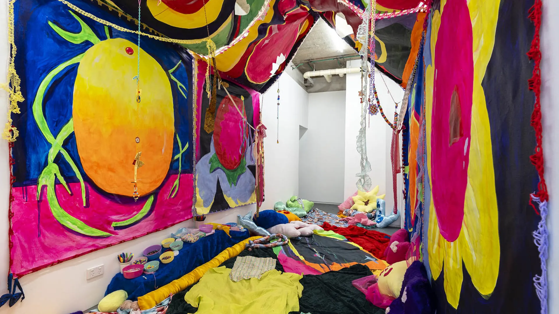 A room with brightly coloured tapestries on the walls and throw rugs on the floor